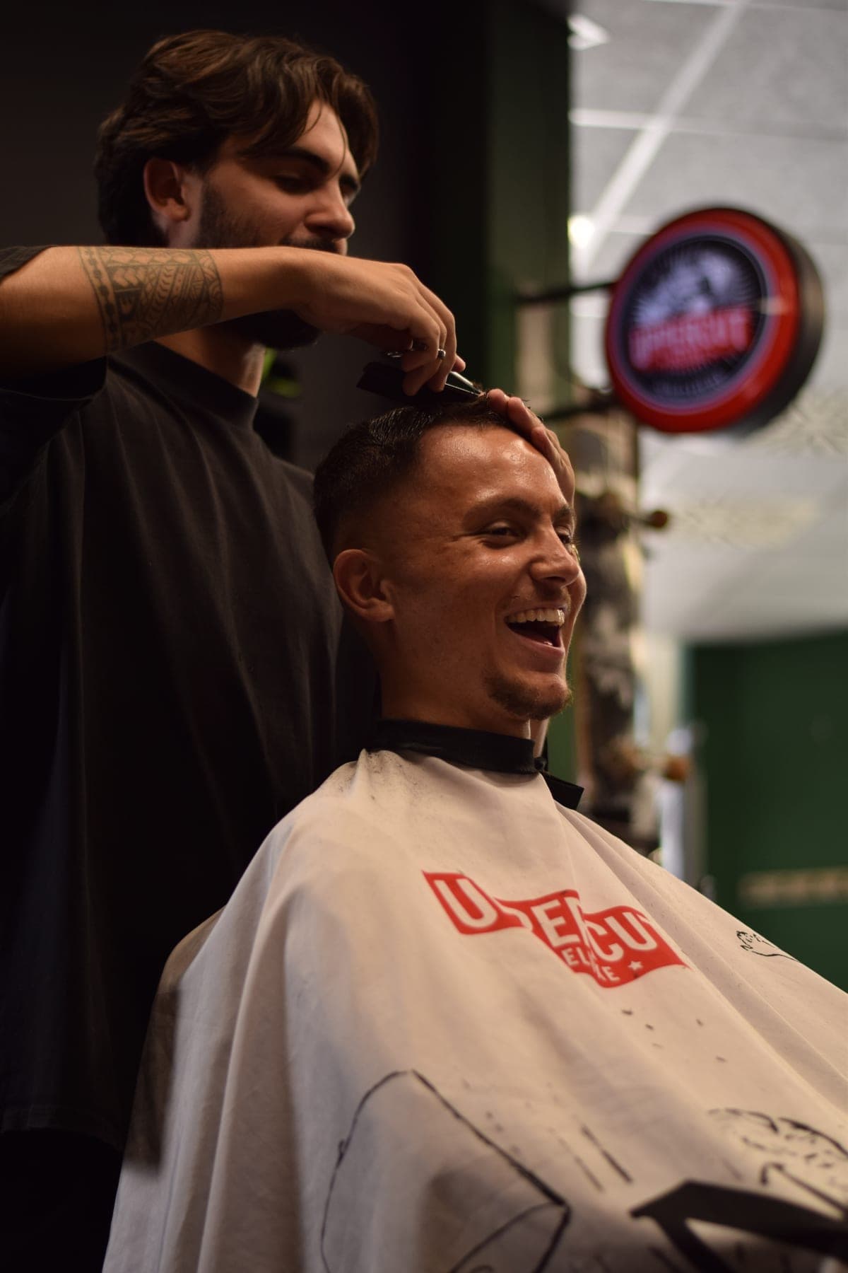 Barber cutting the hair of a smiling bearded client at Porem Barbershop Amsterdam